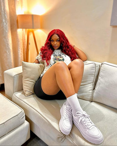 A woman with vibrant red hair sits on a light beige sofa, wearing a white graphic t-shirt, black shorts, white crew socks, and white platform original and authentic PUMA sneakers from Kicks Kenya.

Kicks Kenya has grown to be the premium multi-brand store in East Africa.